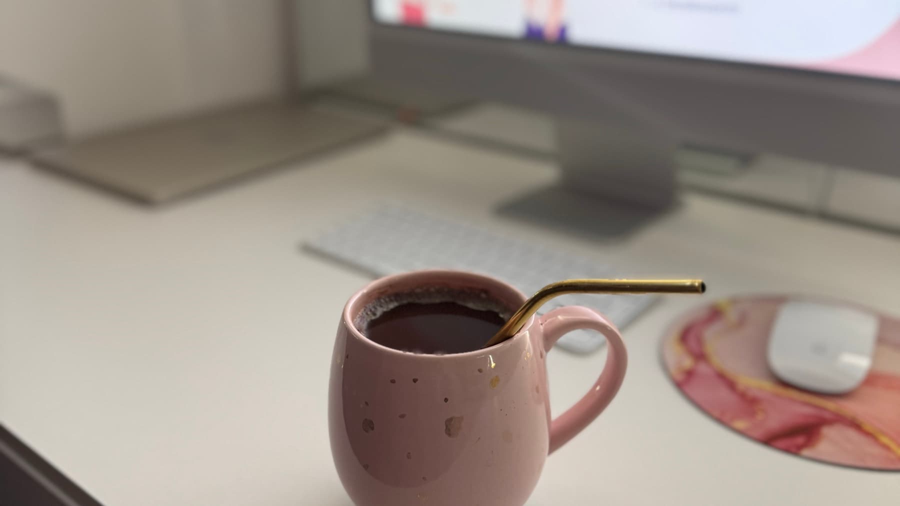Kubek kawy na biurku, w tle monitor z materiałem do angielskiego i klawiatura