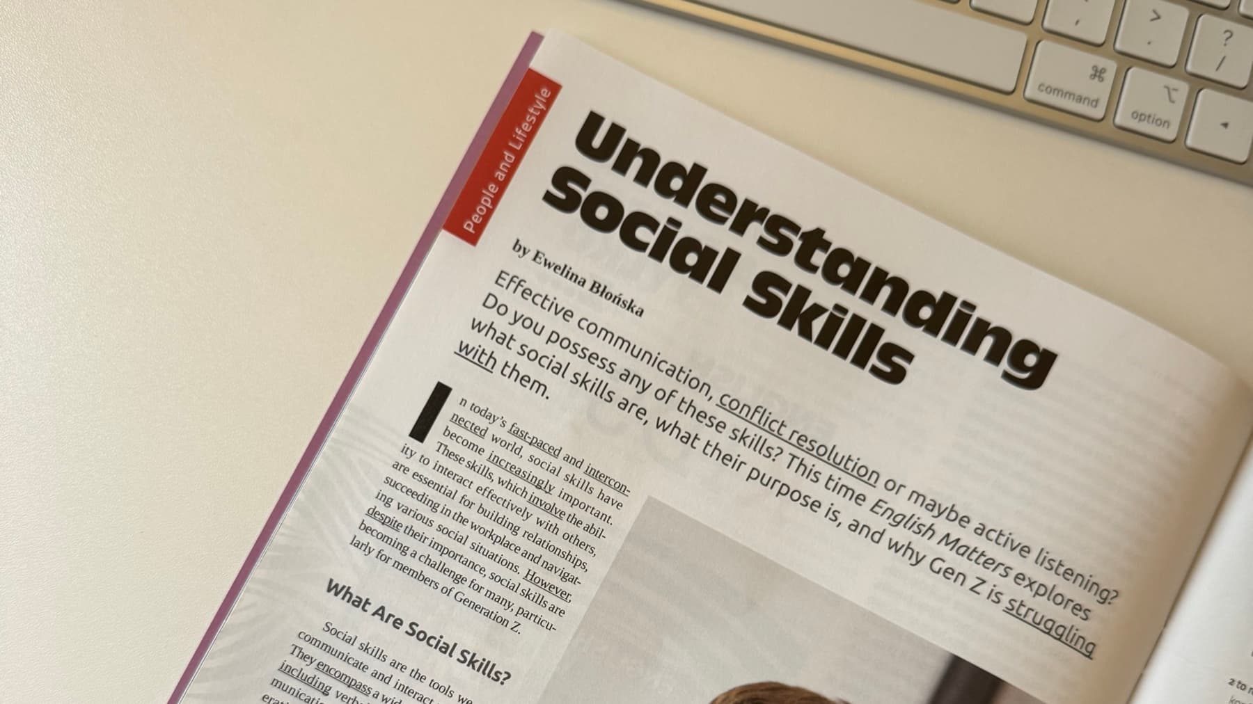 Anglojęzyczny magazyn otwarty na artykule Understanding Social Skills, leżący obok klawiatury